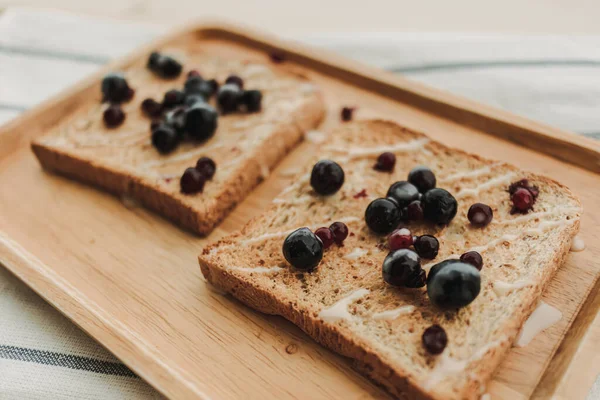 Bayas mixtas pan tostado servido en plato de madera. — Foto de Stock