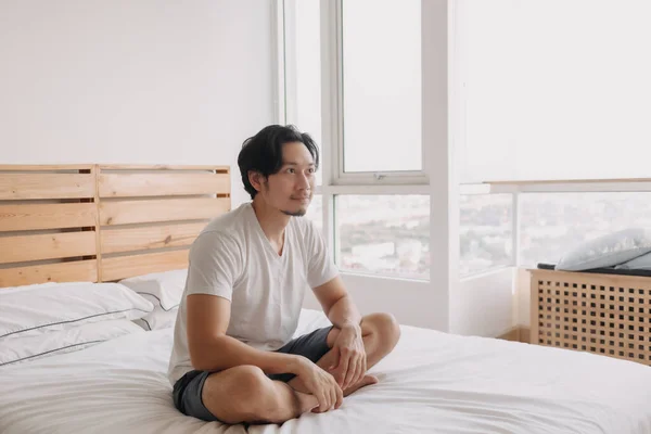 Homem feliz senta-se e relaxar em sua cama em seu apartamento. — Fotografia de Stock