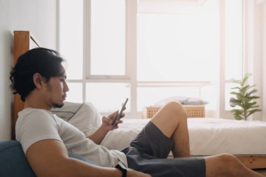 Adam kendini rahatlamış hissediyor ve evinde akıllı telefon kullanıyor..