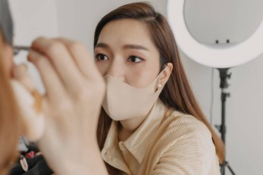 Makyaj sanatçısı müşteri gözlerine makyaj yapıyor.