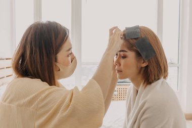 Makyaj sanatçısı müşteri gözlerine makyaj yapıyor.