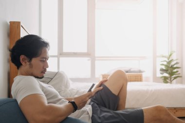 Adam kendini rahatlamış hissediyor ve evinde akıllı telefon kullanıyor..