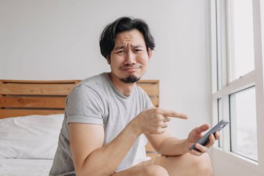 Üzgün adamın internette kötü haberleri var ve akıllı telefondan hayal kırıklığına uğruyor..