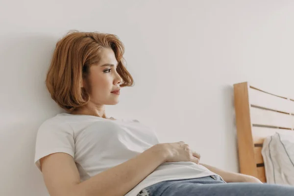 Прикольная женщина в джинсах и белой футболке отдыхает в своей квартире. — стоковое фото