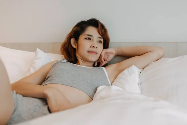 Mujer sexy se siente relajarse en la cama solo en la habitación. —  Fotos de Stock