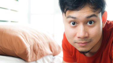 Yatakta Asyalı adamın yüzünü kapatmak.