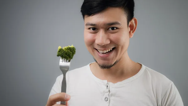 Un uomo asiatico mangia broccoli . — Foto Stock