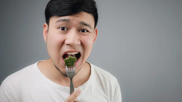 Un hombre asiático come brócoli . — Foto de Stock