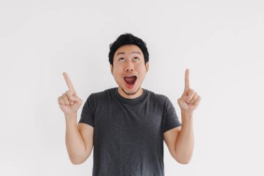Gri tişörtlü Asyalı bir erkek parmak kaldırarak şaşkınlık ve vurgu yapıyor.