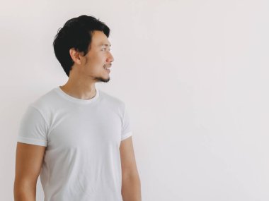Beyaz tişörtlü Taylandlı erkek, evde dikilirken sakin ve düşünceli bir ifade takınıyor, Asyalı kökenli.
