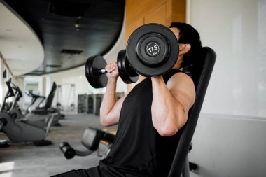 Modern fitness merkezinde göğüs ve kolları çalıştıran erkek sporcu.