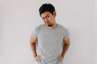 Genç Asyalı erkek şüpheli ve şüpheli bir vücut ifadesiyle poz veriyor.