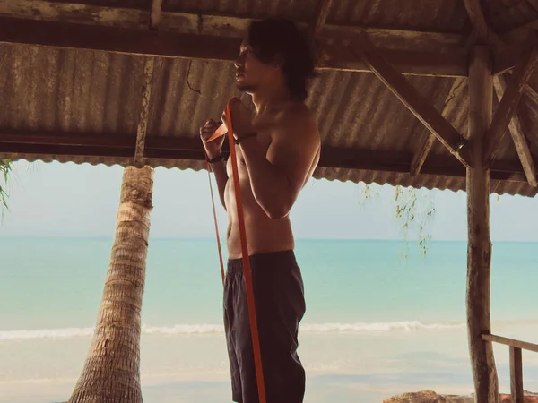 Deniz kenarındaki kulübede lastik bant ile egzersiz ve egzersiz. Asya 'da plaj rahatlığı..