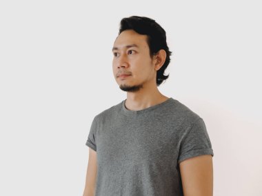 Tarz sahibi gri gömlekli genç bir adam düşünceli bir şekilde uzaktaki minimalist bir estetiği somutlaştırıyor.