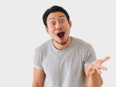 Yüzünde şaşırmış bir ifade olan bir adam gri bir gömlek giyiyor. O, parmağını işaret ediyor ve bir jest yapıyor. Sürpriz ve merak kavramı