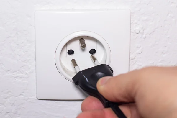 Hand plugs cord in socket