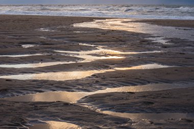 Yazın Cadzand 'ın kumlu sahillerindeki su birikintilerine yansıyan güneş.