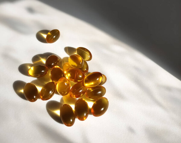 Изображение некоторых капсул рыбного жира, сияющих вечерними солнечными лучами. Изображение сделано вечером.