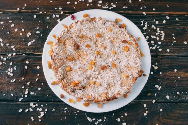 Tahta bir masada yuvarlak şekilli yulaf ezmeli turta. Kuru üzüm ve gevrek serpiştirilmiş. Yukarıdan görüntüle