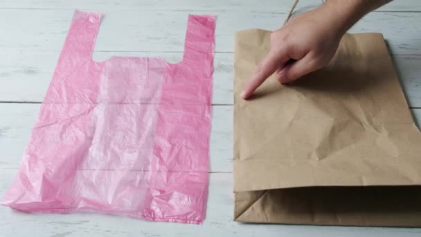 Mano masculina señala con un dedo para elegir entre una bolsa de plástico y una bolsa de papel. — Vídeos de Stock