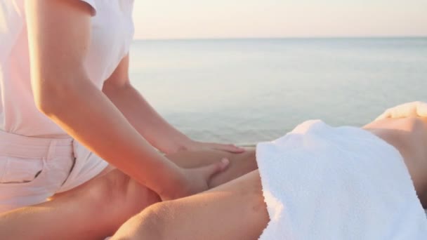 Flicka massage terapeut gör en fot massage till en kvinna på stranden. — Stockvideo