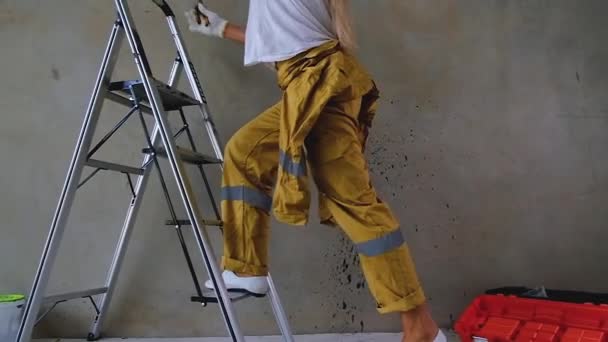 制服を着た電気技師の少女が階段を登り ワイヤーを使い始める スローモーション 床に道具箱がある — ストック動画