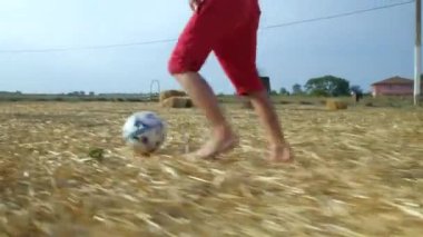 Genç adam elinde futbol topuyla sahada koşuyor.
