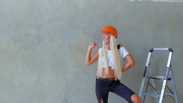 Das Blonde Vorarbeitermädchen Mit Dem Harten Hut Lächelt Und Zeigt — Stockvideo
