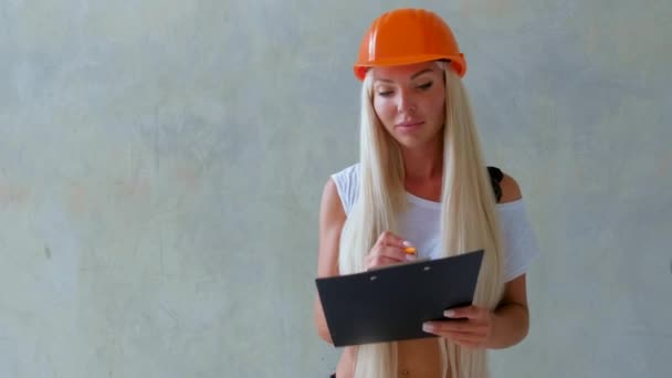 헬멧을 콘크리트 가까이에서 건축자 소녀는 문서에 들어가게 머리를 건축중인 — 비디오
