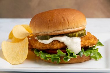  Hamburg çöreğinde servis edilen marul, domates ve turşulu tavuk göğsü.