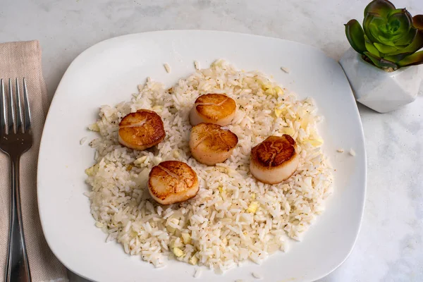 Beyaz pirinçle servis edilen tavada istiridye soğan ve sarımsak var.