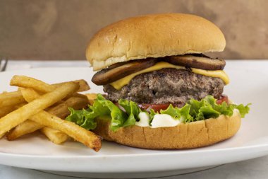 cheese burger  with lettuce and tomatoes  served with french fries
