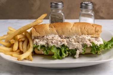 Soğanlı tavuk salatası ve patates kızartmasıyla servis edilen bir alt rulo marul.