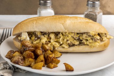 Ekmek arası sosisli omlet ve yanında patates kızartması.