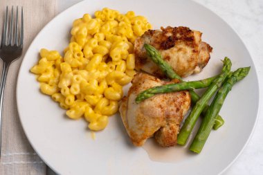 Baharatlı tavuk butları, peynirli makarna ve kuşkonmaz.