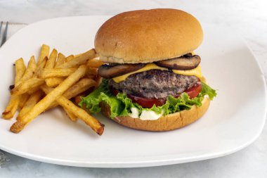 cheese burger  with lettuce and tomatoes  served with french fries