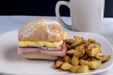  jambon ve çırpılmış yumurtalı sandviç, yanında patates kızartması.