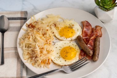 Kızarmış yumurtanın üstü maydanozlu, doğranmış mücver, sosis ve pastırmayla servis ediliyor., 