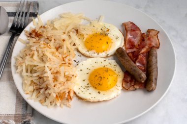 Kızarmış yumurtanın üstü maydanozlu, doğranmış mücver, sosis ve pastırmayla servis ediliyor., 