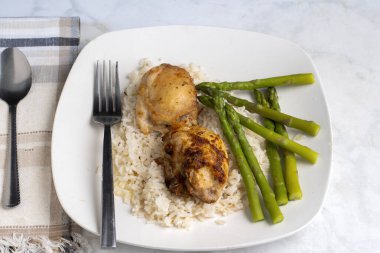  Beyaz pirinç ve kuşkonmazla servis edilen çivili kalçalar.