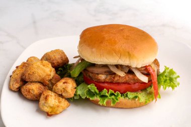 Sebzeli burger üstü soğanlı, biberli ve sebzeli patates ile servis edilen mantarlı., 