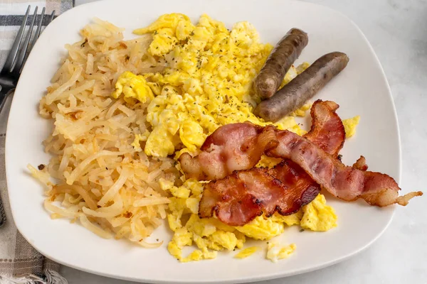 domuz pastırması ve sosis ile servis edilen çırpılmış yumurta ve kıymalı patates kızartması.