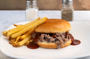   Patates kızartmasıyla servis edilen ekmeğin üzerinde barbekü soslu doğranmış biftek.