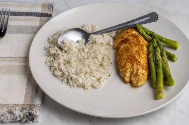 Baharatlı pirinç ve fesleğenle servis edilen tavuk göğsü.