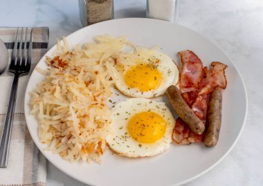 Kızarmış yumurtanın üstü maydanozlu, doğranmış mücver, sosis ve pastırmayla servis ediliyor., 