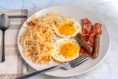 Kızarmış yumurtanın üstü maydanozlu, doğranmış mücver, sosis ve pastırmayla servis ediliyor., 