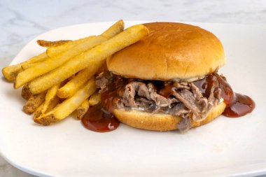   Patates kızartmasıyla servis edilen ekmeğin üzerinde barbekü soslu doğranmış biftek.