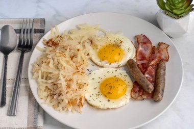 Kızarmış yumurtanın üstü maydanozlu, doğranmış mücver, sosis ve pastırmayla servis ediliyor., 