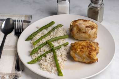  Beyaz pirinç ve kuşkonmazla servis edilen tavuk butları..