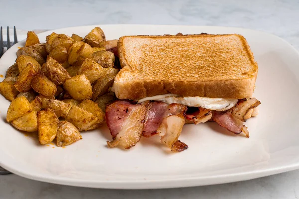 Kızarmış yumurta ve pastırmalı peynirli sandviç. Yanında da patates kızartması..